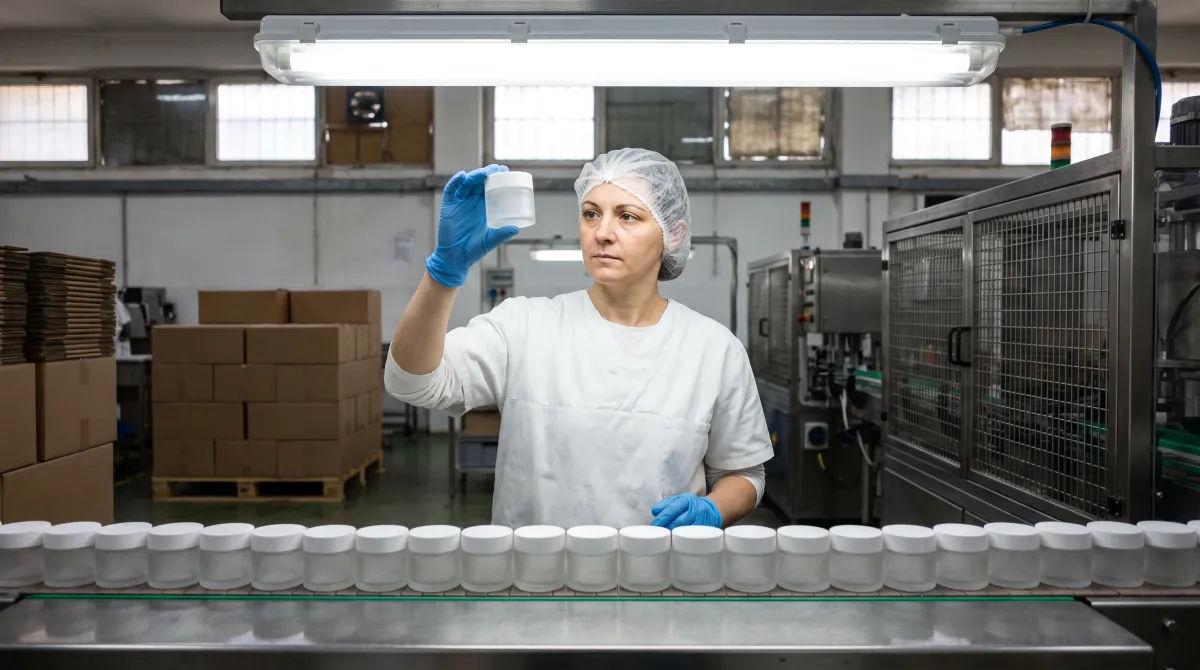 Opératrice contrôlant un pot vide sur une ligne de conditionnement, règlement PPWR emballages cosmétiques