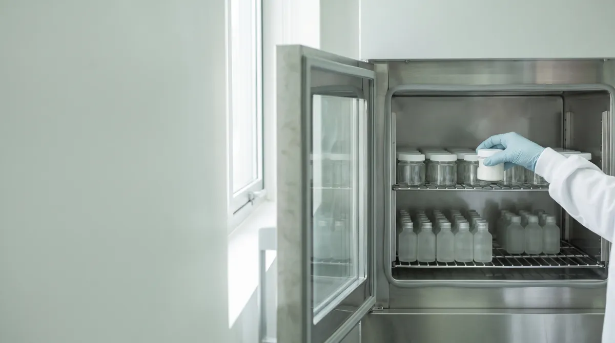 Technician placing a cream jar in a stability test chamber, a key step before mass production