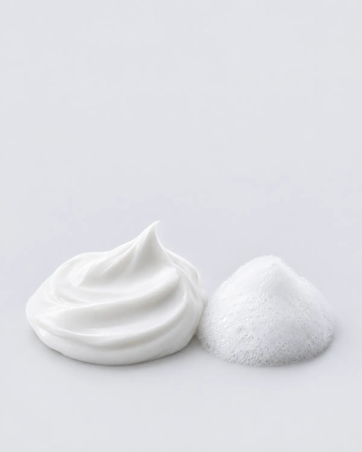 sublime clariderm cream and foam | Carmel Cosmetics Labs Textures de crème blanche et de micro-mousse sur un fond de studio gris clair